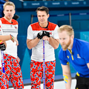 Norges Torger Nergård, Håvard Vad Petersson och Thomas Ulserud ser på när Sveriges Niklas Edin lägger en sten under curlingmatchen mellan Sverige och Norge.