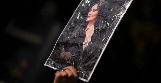 Illustrationsbild. Demonstrant håller upp ett porträtt av Mahsa Amini, vars död utlöste protesterna.  Peter Dejong / AP
