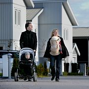 Familj på promenad i ett nybyggt villaområde. Illustrationsbild.