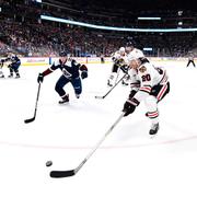 Chicago Blackhawks Brandon Saad sträcker sig efter pucken med Colorado Avalanches Samuel Girard i bakgrunden. 