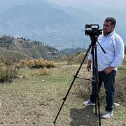 En journalist spelar in en intervju med en man i Kashmir under en mediaresa organiserad av regeringen.