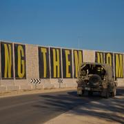 Ett israeliskt militärfordon passerar texten ”ta hem dem nu” på en mur som avskärmar Gaza från Israel.