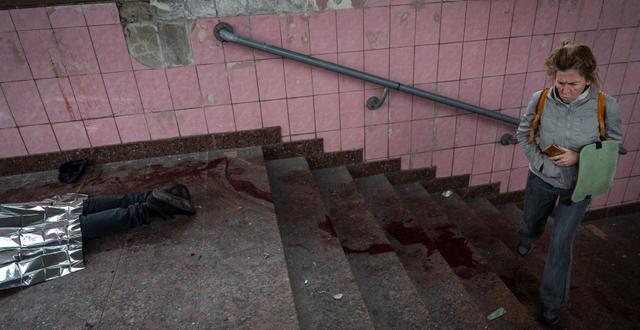 En kvinna går förbi kroppen till en av de personer som dog i torsdagens attacker.  Bernat Armangue / AP