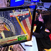 Illustrationsbild. Tradern Phyllis Arena Woods med Fed-chefen Jerome Powell på skärmen.