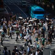 Tokyobor bär paraplyer för att skydda sig mot solen.