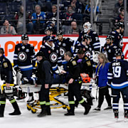 Winnipegs Haydn Fleury får hjälp att komma av isen efter olyckan.