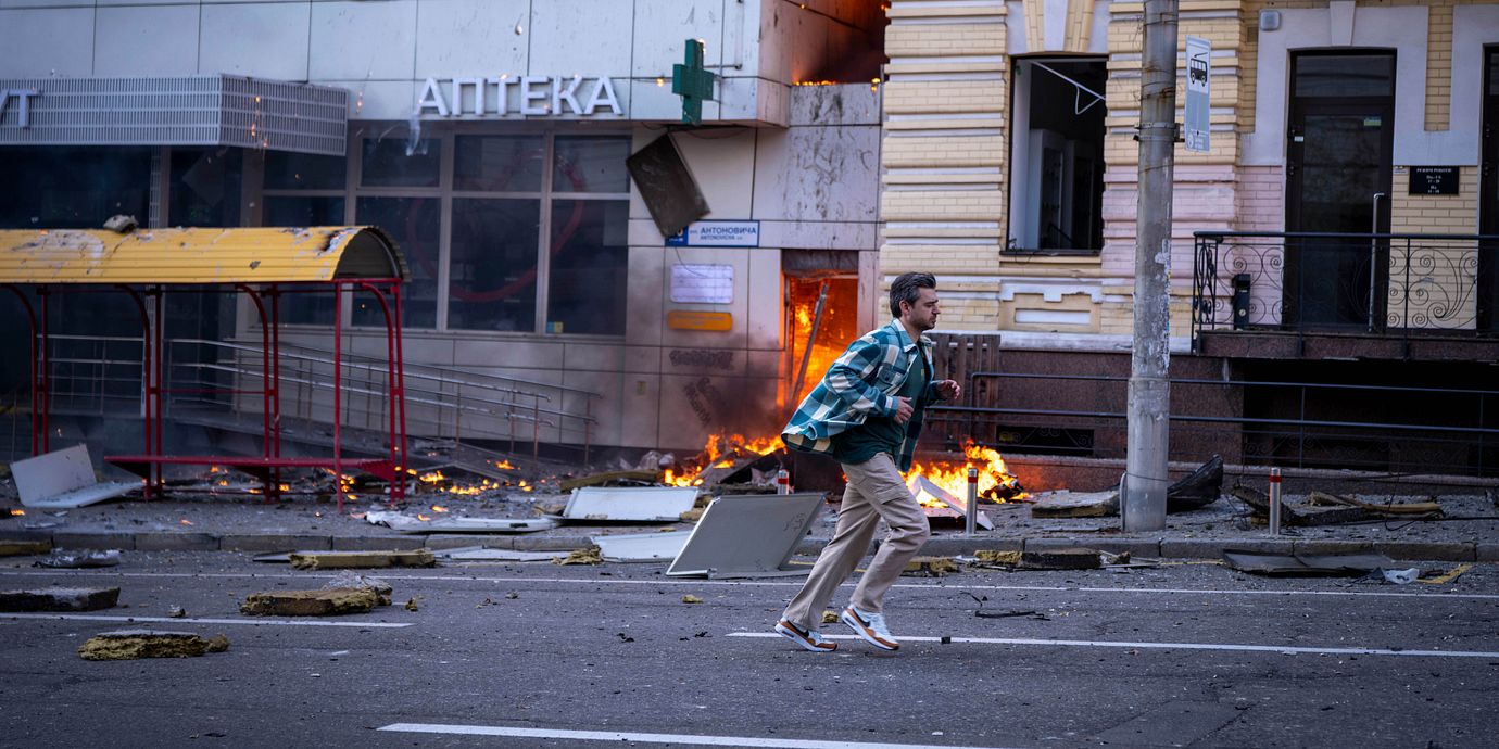 En man springer framför ett sjukhus som träffats av en rysk drönarattack i centrala Kyjiv.