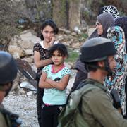 Israeliska soldater och palestinska flickor vid attentatsplatsen i Hebron.