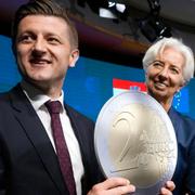 Kroatiens förra finansminister Zdravko Maric håller upp ett tvåeuromynt i kartong i samband med att europlanerna fastställdes. Till höger Europeiska centralbankens ordförande Christine Lagarde.