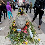 Ett betonglejon täckt av blommor på Drottninggatan.