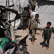 Palestinier som samlas kring en bil som träffats i en israelisk attack under torsdagen.