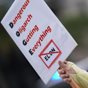 81-åriga Judy Homer protesterar utanför en Tesla-återförsäljare i Miami med en skylt riktad mot Elon Musks myndighet Doge. Arkivbild från den 29 mars 2025