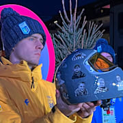 Vladyslav Heraskevytj håller upp hjälmen med bilder på dödade atleter.