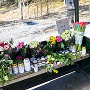 Minnesplats med tända ljus och blommor vid busshållplatsen där en 18-åring sköts till döds på en SL-buss.