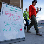 Invånare passerar en skylt utanför en restaurang med texten: ”Tumbler Ridge är starkt. Vi är med er.”