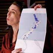 Jacinda Ardern håller upp en karta som visar landets nya utbrott. 