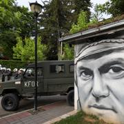 Polish soldiers, part of the peacekeeping mission in Kosovo KFOR guard a street past graffiti depicting former Bosnian Serb wartime general Ratko Mladic, in the town of Zvecan, northern Kosovo, Monday, May 29, 2023. 