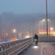 En cyklist cyklar mot Slussen från Gamla stan i Stockholm i dimmigt vinterväder. Arkivbild.