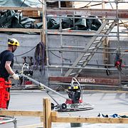En byggarbetare slipar betong på en byggarbetsplats.