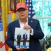 Trump visar upp en bild på honom och Putin. Bredvid honom står Fifas president Gianni Infantino.