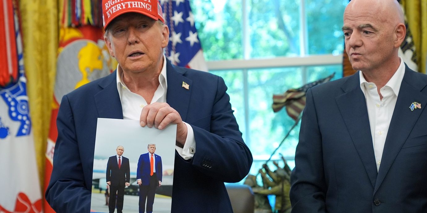 Trump visar upp en bild på honom och Putin. Bredvid honom står Fifas president Gianni Infantino.