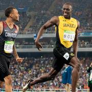 Usain Bolt och Andre de Grasse ler mot varandra vid mållinjen