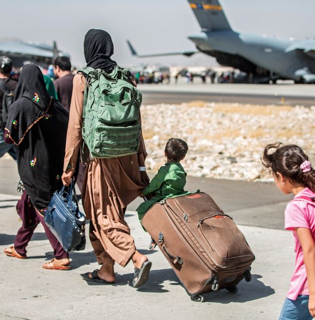 In this file photo, provided by the U.S. Marine Corps, families walk towards their flight during ongoing evacuations at Hamid Karzai International Airport, in Kabul, Afghanistan, on Aug. 24, 2021. Sgt. Samuel Ruiz / AP