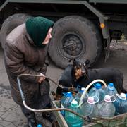 En äldre kvinna drar vattenflaskor på en vagn i ryskockuperade Donetsk. 