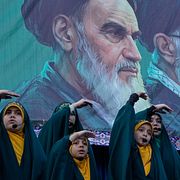 Flickor sjunger framför porträtt av iranska ledare i Teheran.