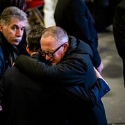 Nicolas Feraud kramar om en besökare under minnesceremonin den 9 januari.