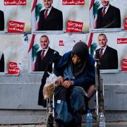 Hemlös kvinna framför valaffischer i Beirut. 