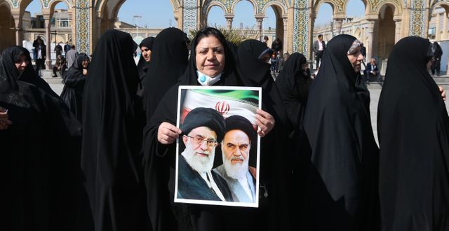 En iransk kvinna med ett porträtt på ayatollorna Khamenei och Khomeini. ATTA KENARE / TT NYHETSBYRÅN