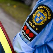 Ordningsvakt som arbetar för Securitas vid en polisbil i samband en rättegång. 