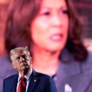 Donald Trump med Kamala Harris i bakgrunden. 