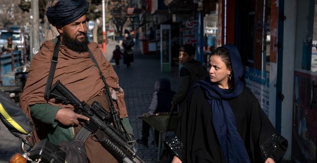 En kvinna går förbi en taliban på Kabuls gator i december 2022.  Ebrahim Noroozi / AP