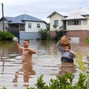 Invånare vadar igenom den översvämmade staden Lismore i Australien. 
