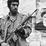 Against the background of a wall covered with posters an Iranian stands guard in front of the United States embassy compound in Tehran on Wednesday, Nov. 7, 1979. Students stormed the embassy Sunday, Nov. 4 and are holding the staff hostage against the deportation of the former Shah of Iran from the United States.