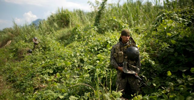 In this Sept. 19, 2014 photo, a soldier stands guard during the destruction of a clandestine airstrip in the Valley of the Apurimac, Ene and Mantaro River Valleys, or VRAEM, the world's No. 1 coca-growing region in Ayacucho, Peru.  Rodrigo Abd