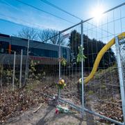 Ett Öresundståg passerar på söndagen bakom blommor och ljus som fästs i det staket som efter olyckan satts tillbaka vid Kulltorpsskolan i Kristianstad efter fredagens olycka