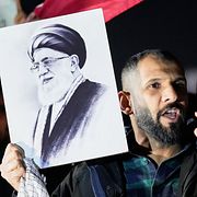 En man håller upp ett porträtt av Ali Khamenei under en demonstration.