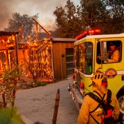 Brandmän arbetar med att släcka ett hus som börjat brinna på grund av skogsbränderna.