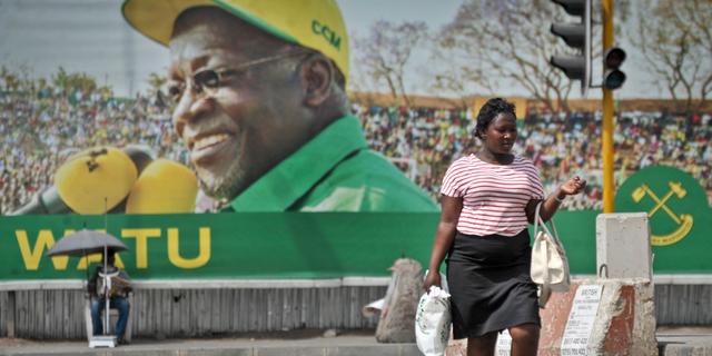 En kvinna i Dar es Salaam i Tanzania vandrar förbi en stor skylt med Tanzanias president John Magufulis ansikte. Khalfan Said / TT NYHETSBYRÅN