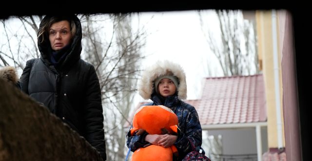 En kvinna och hennes dotter går till ett skyddsrum under en pågående rysk attack mot Mariupol, 24 februari, 2022. Illustrationsbild.  Sergei Grits / AP