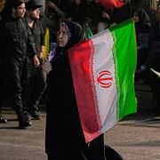 En kvinna bär på den iranska flaggan.