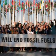 Members of Greenpeace gather for a photo around a sign that reads "we will end fossil fuels" at the COP28 U.N. Climate Summit, Wednesday, Dec. 13, 2023, in Dubai, United Arab Emirates.