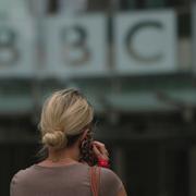 En kvinna talar i telefon utanför BBC:s huvudkontor i London. 