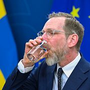 Socialminister Jakob Forssmed (KD) dricker ett glas vatten under en pressträff.