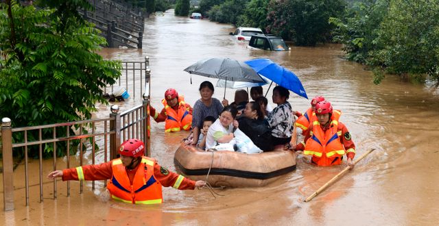 Räddningsarbetare evakuerar invånare på en flotte genom översvämningsdrabbade i Jiujiang i Kina i juli 2020.  AP