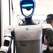 Illustrationsbilder: En skolelev vid dator och en Unitree-robot, det märke som skolan i Västerås köpt in.