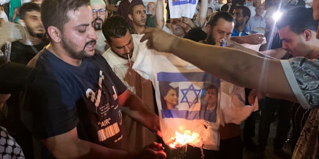 Demonstranter bränner en tröja med Najla al-Mangoush och Eli Cohens ansikten. Yousef Murad / AP